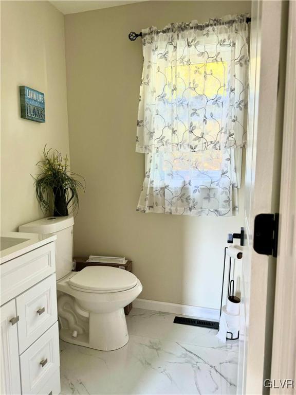 bathroom with marble finish floor, visible vents, toilet, vanity, and baseboards