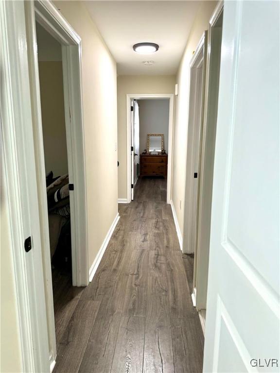 hallway featuring baseboards and dark wood-style flooring