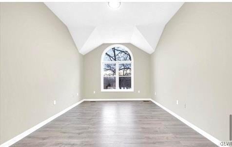 bonus room featuring vaulted ceiling, baseboards, and wood finished floors