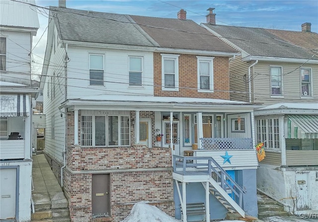 view of property featuring covered porch, roof with shingles, a chimney, and brick siding