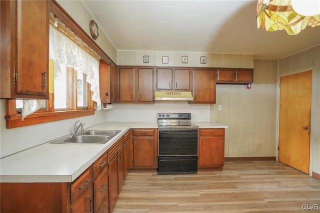 kitchen featuring brown cabinetry, range with electric cooktop, light countertops, and under cabinet range hood