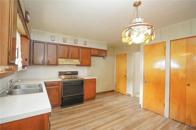 kitchen featuring hanging light fixtures, light countertops, under cabinet range hood, a sink, and range with electric stovetop