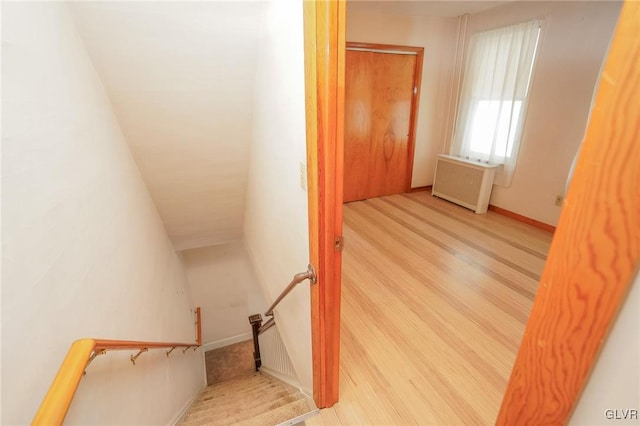 staircase featuring radiator heating unit, wood finished floors, and baseboards