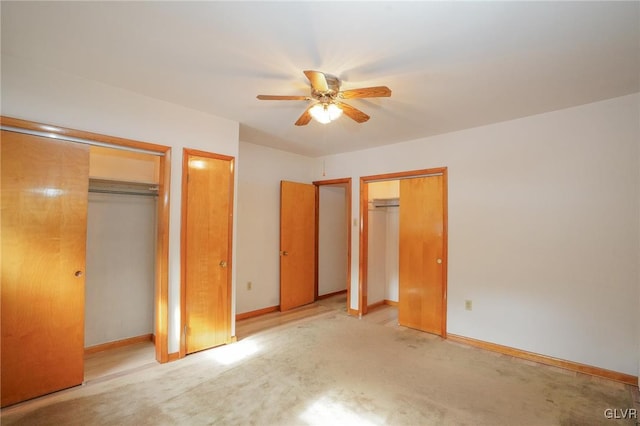 unfurnished bedroom featuring multiple closets, light colored carpet, baseboards, and a ceiling fan