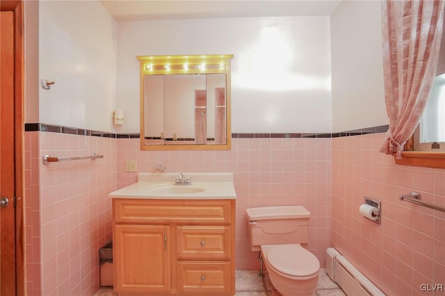 bathroom with wainscoting, toilet, vanity, a baseboard heating unit, and tile walls