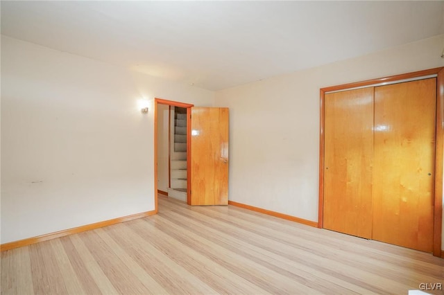 unfurnished bedroom featuring baseboards, a closet, and light wood-style floors