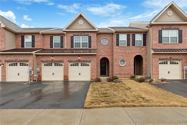 townhome / multi-family property with brick siding, driveway, and an attached garage