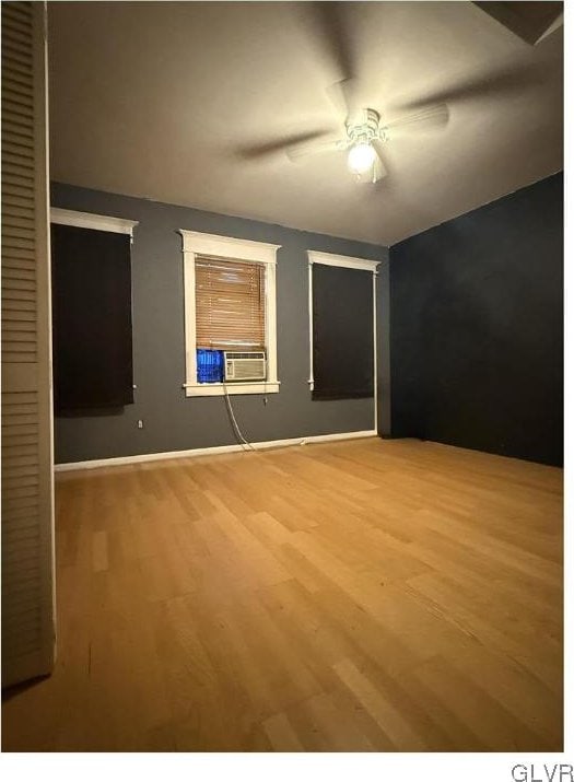 unfurnished bedroom with ceiling fan, a closet, cooling unit, and wood finished floors