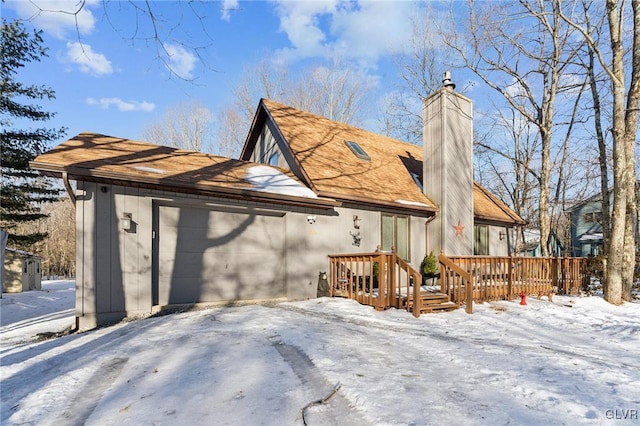 exterior space featuring a deck, a shingled roof, a chimney, and a garage