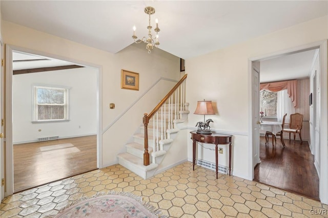 foyer with visible vents, light wood-style flooring, a chandelier, baseboards, and stairs