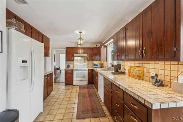 kitchen featuring tile counters, decorative backsplash, a sink, white appliances, and under cabinet range hood