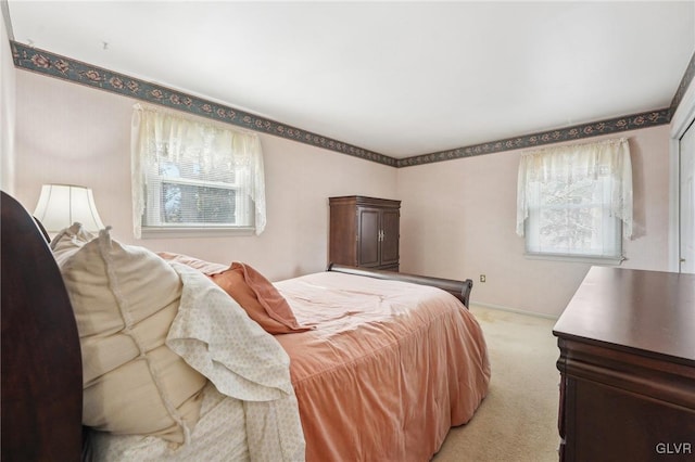 bedroom featuring light carpet, multiple windows, and baseboards