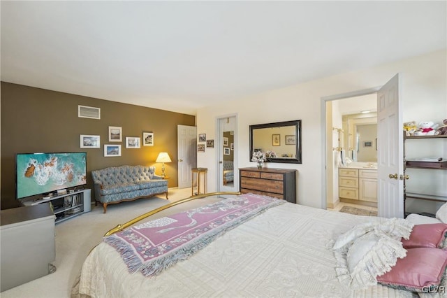 bedroom with light colored carpet, visible vents, and ensuite bathroom