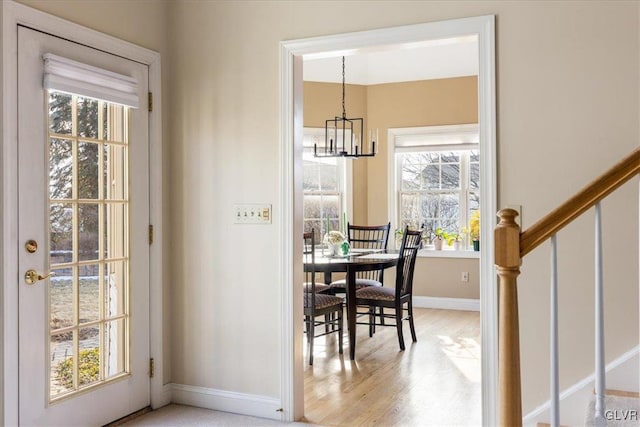 dining room with stairs, a notable chandelier, baseboards, and light wood-type flooring