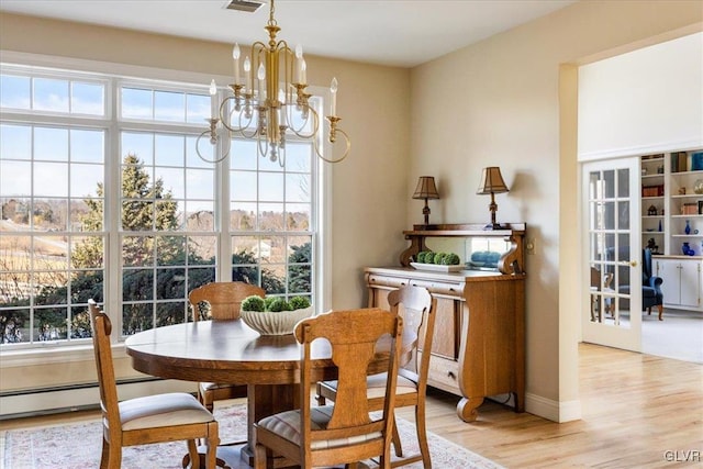 dining room with a baseboard heating unit, a healthy amount of sunlight, a chandelier, and light wood finished floors