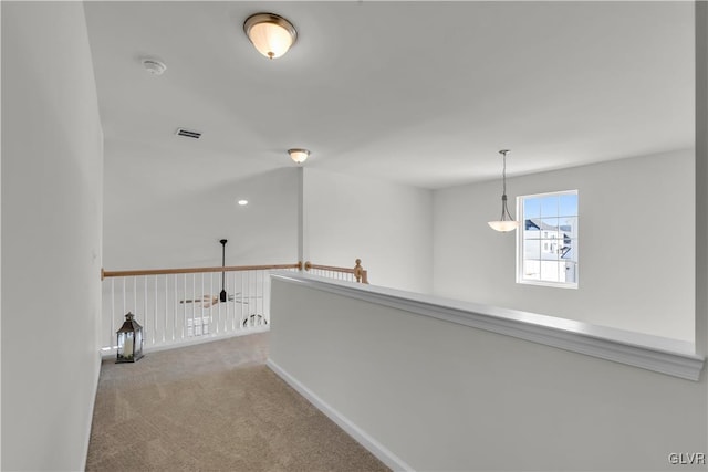 corridor featuring light carpet, visible vents, and baseboards