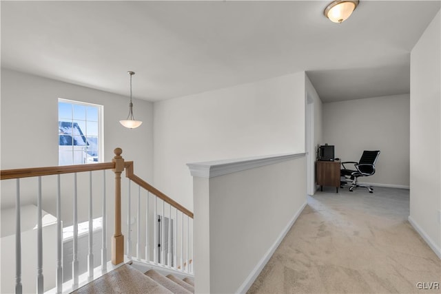 hallway featuring baseboards, light colored carpet, and an upstairs landing