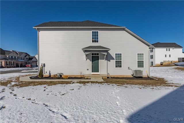 snow covered back of property featuring cooling unit and a residential view