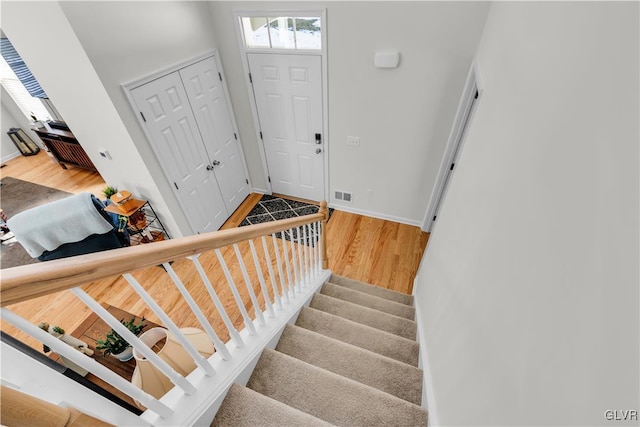 stairway featuring visible vents, baseboards, and wood finished floors