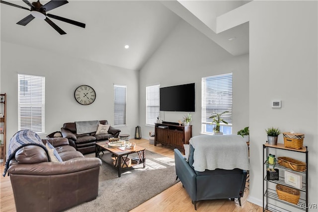 living area featuring light wood-style floors, ceiling fan, high vaulted ceiling, and baseboards