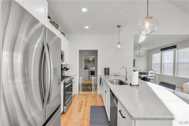 kitchen with light stone counters, pendant lighting, stainless steel appliances, white cabinetry, and a sink