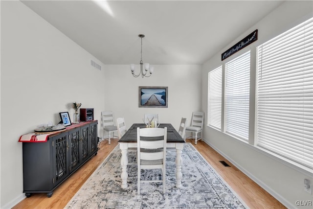 dining room featuring baseboards, visible vents, light wood finished floors, and an inviting chandelier