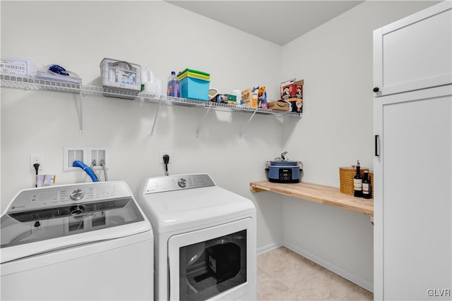 clothes washing area with washing machine and dryer, laundry area, and baseboards