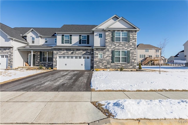 view of front of house featuring driveway, stone siding, an attached garage, and a residential view