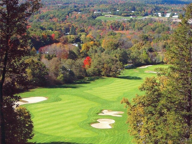 exterior space with a view of trees, golf course view, and a lawn