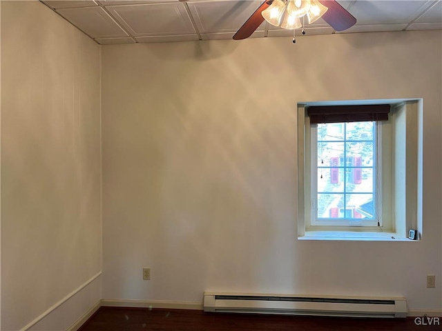 spare room with a baseboard heating unit, dark wood-style floors, baseboards, and a ceiling fan