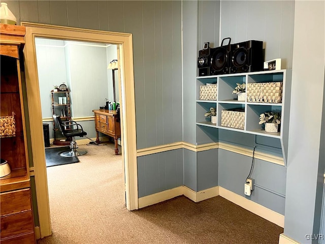 hallway featuring dark colored carpet and baseboards