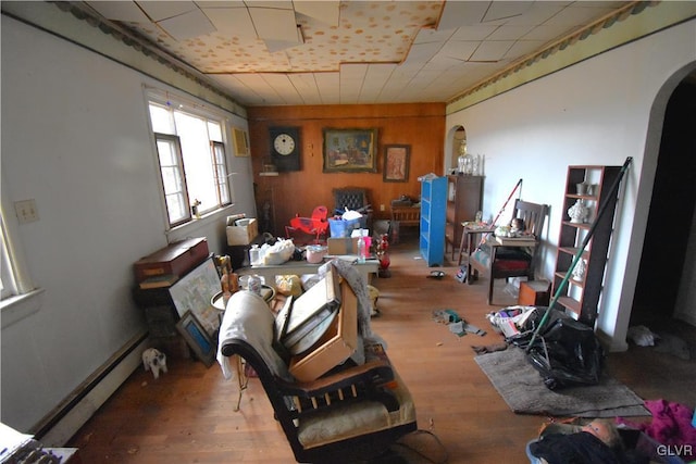 interior space featuring a baseboard heating unit, arched walkways, and wood finished floors