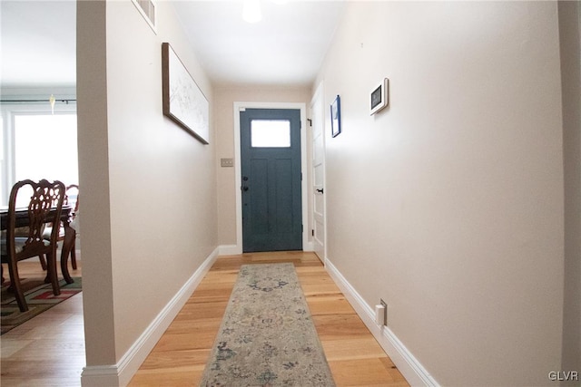 entryway with light wood-type flooring, a healthy amount of sunlight, visible vents, and baseboards