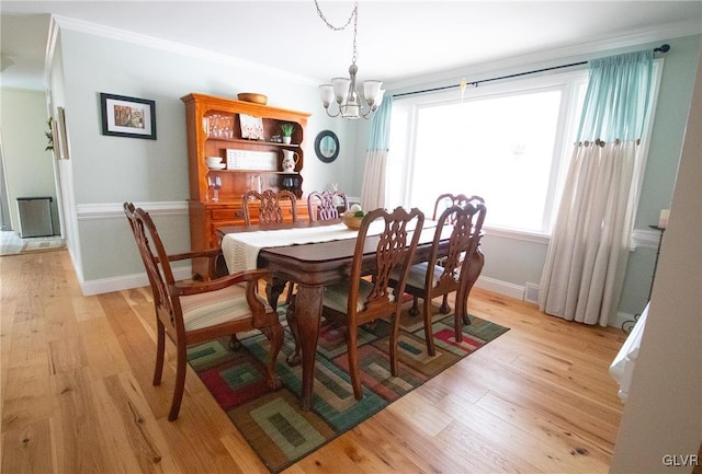 dining room featuring a notable chandelier, crown molding, light wood-style flooring, and baseboards