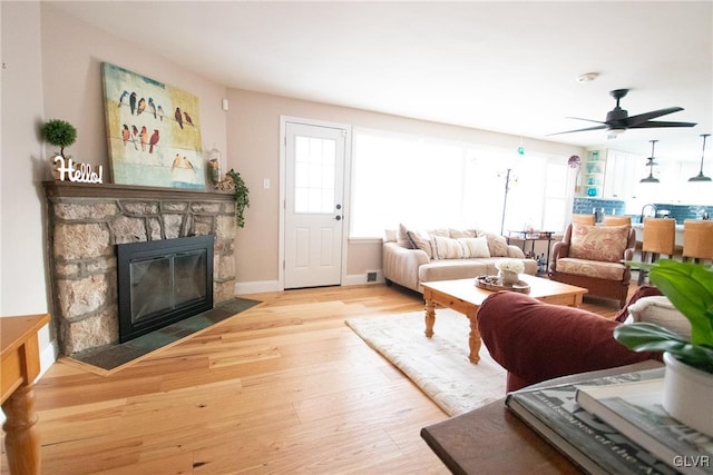 living area with a wealth of natural light, a fireplace, baseboards, and wood finished floors