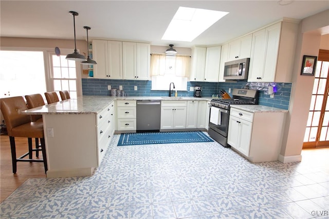 kitchen with pendant lighting, a breakfast bar area, stainless steel appliances, a sink, and a peninsula