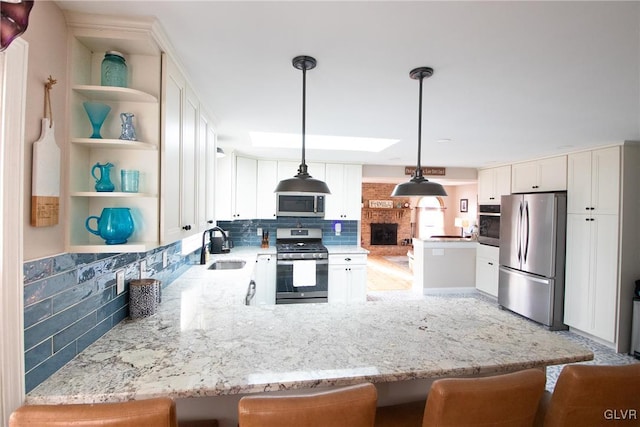 kitchen featuring a peninsula, appliances with stainless steel finishes, a kitchen bar, and open shelves