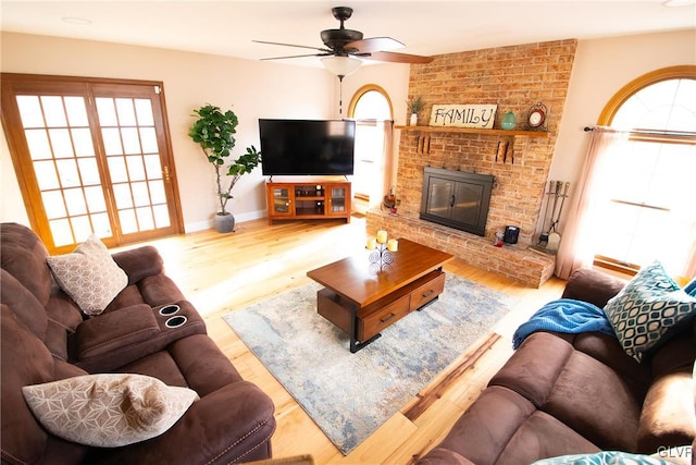 living room with baseboards, a fireplace, a ceiling fan, and wood finished floors