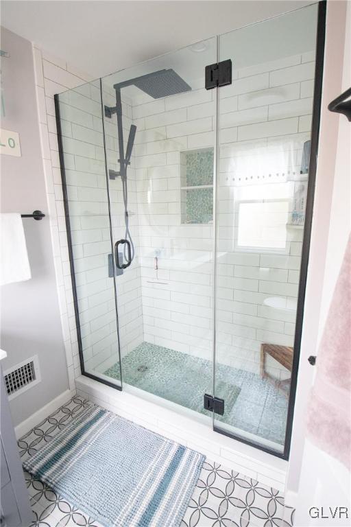 full bathroom featuring a stall shower, baseboards, visible vents, and tile patterned floors