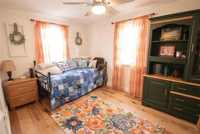 bedroom with ceiling fan, multiple windows, light wood-style flooring, and crown molding