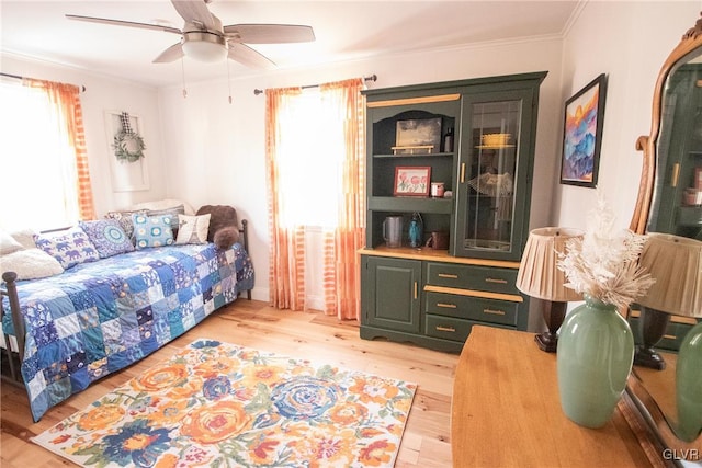 bedroom featuring light wood-style floors, a ceiling fan, and crown molding