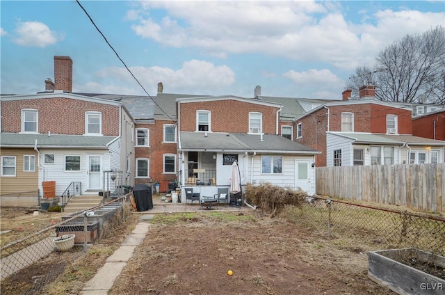 back of property featuring a vegetable garden, a patio area, a fenced backyard, and a residential view