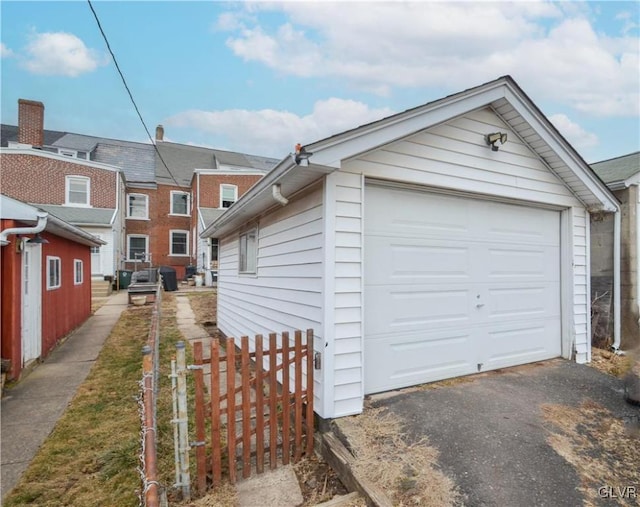 detached garage featuring aphalt driveway and fence