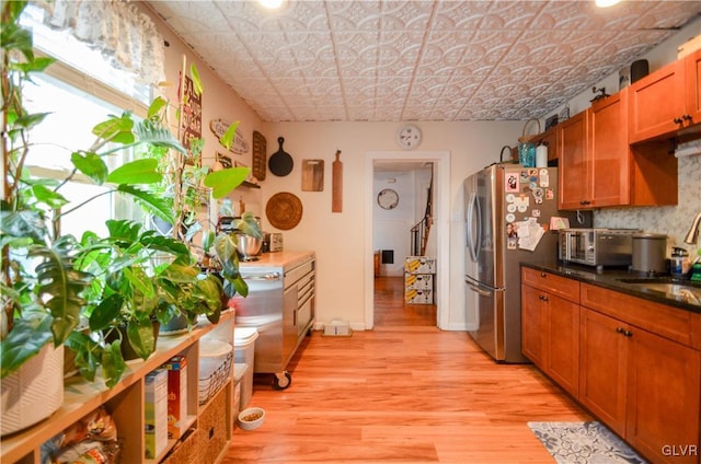 kitchen featuring an ornate ceiling, brown cabinets, freestanding refrigerator, light wood-style floors, and a sink