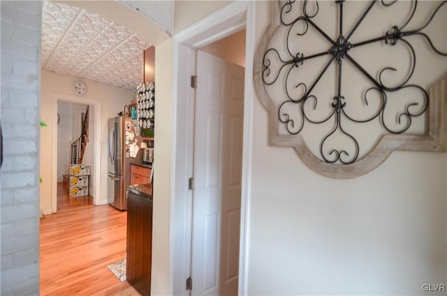 hallway featuring wood finished floors, an ornate ceiling, and baseboards