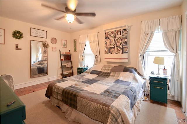 bedroom with a ceiling fan, baseboards, and wood finished floors