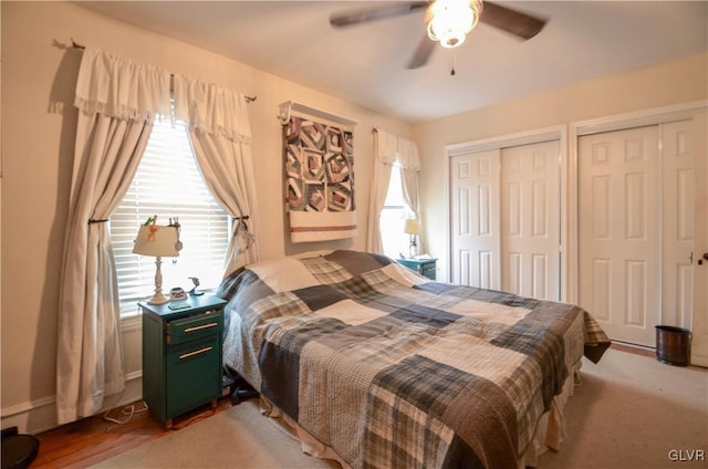 bedroom featuring ceiling fan, multiple windows, and multiple closets