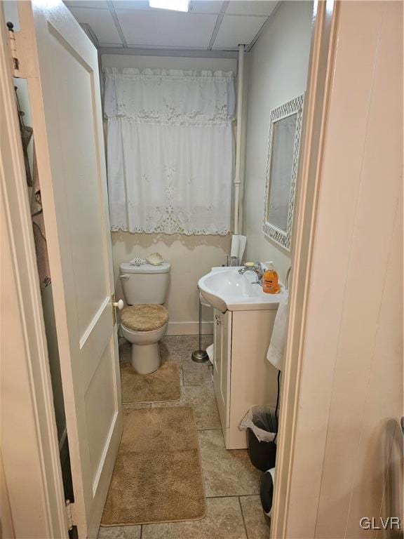 bathroom with toilet, a paneled ceiling, and vanity