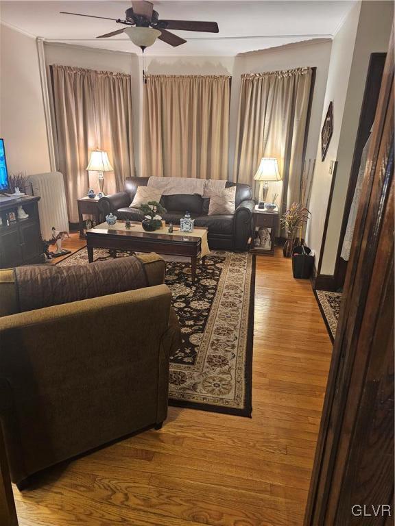 living area featuring radiator heating unit, ceiling fan, and wood finished floors