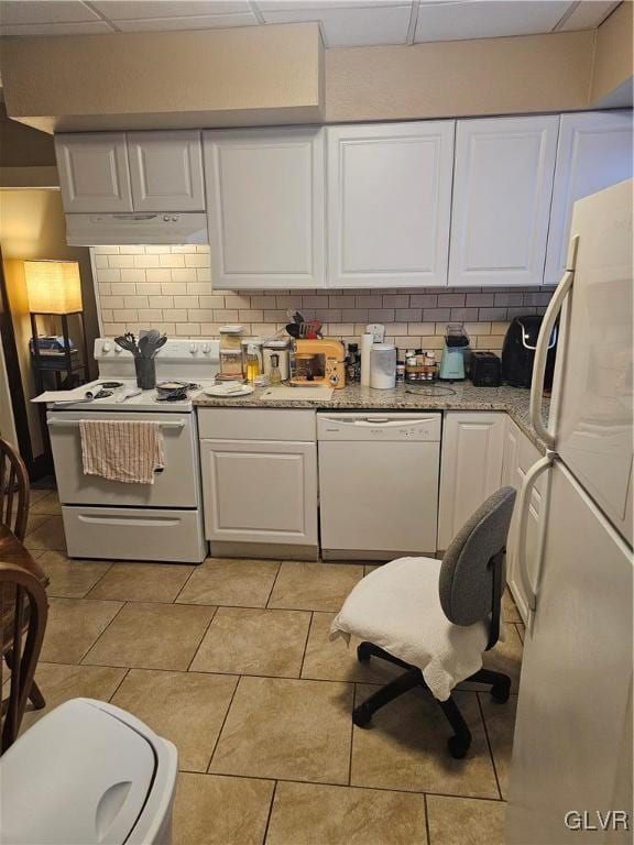 kitchen with tasteful backsplash, white appliances, white cabinets, and under cabinet range hood